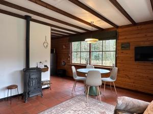 een woonkamer met een tafel en stoelen en een fornuis bij Bed en Boshuisjes in Oisterwijk