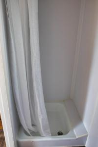 a shower with a white curtain next to a shower at Finnenhaus 4 in Lübeck