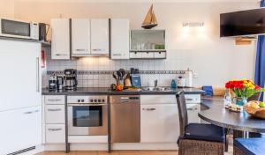 a kitchen with white cabinets and a counter top at 4 Sterne-Terrassen-Fewo "Heimathaven" direkt am Ostseestrand inkl Schwimmbad in Kronsgaard