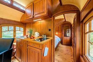 eine Küche mit Holzschränken und ein Bett in einem Zug in der Unterkunft Zigappo Directeur in Lychen