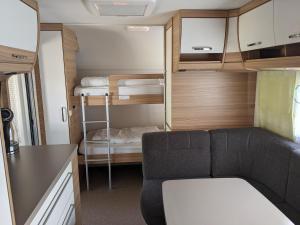 a small caravan with a couch and bunk beds at Luxuswohnwagen Karpfen am Kransburger See 354 in Kransburg