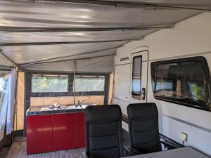 an rv with a sink and chairs in it at Luxuswohnwagen Karpfen am Kransburger See 354 in Kransburg