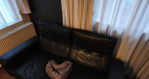 a black leather couch in a room with a window at Ferienwohnung an der Mosel, Postamt in Senheim
