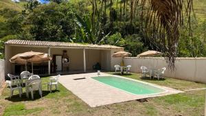 a house with a swimming pool and chairs and umbrellas at Ninho do Vale - Centro Conservatória in Conservatória