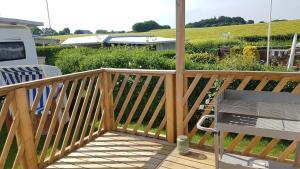 a wooden deck with a bench and a garden at Campingland Ostsee - Mobilheim 016Weitsicht in Schashagen