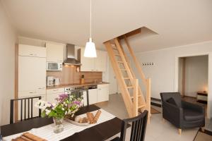 a kitchen and living room with a table and a staircase at Wohnung 2 in Fehmarn +4 photos
