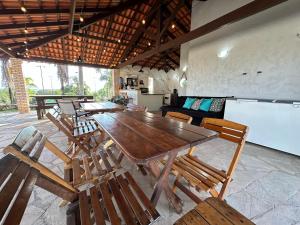 a group of wooden tables and chairs in a room at Chacará de Recanto dos Sonhos - Casa de Temporada in Cidade Ocidental