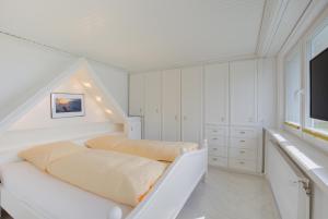 una camera da letto bianca con un letto e una TV di F2 im Haus am Meer a Wenningstedt