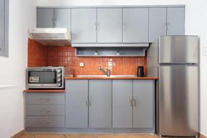 a kitchen with white cabinets and a stainless steel refrigerator at Aristeas Studio in Ornos +3 photos