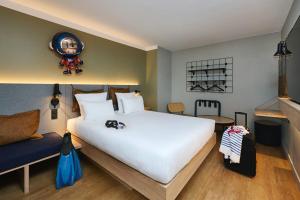 a bedroom with a large white bed and a couch at Moxy Annecy in Annecy