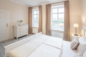 a white bedroom with a large bed and a window at Austernfischer in Westermarkelsdorf +17 photos