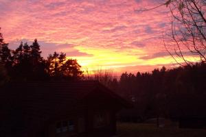 a sunset over a house with trees and a building at Blockhaus Hedwig Haus 10 in Stamsried