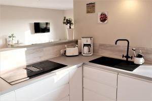 a kitchen with white cabinets and a sink at FEWO Ostseeland in Grömitz +19 photos
