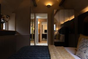 Un dormitorio con una cama con un espejo grande. en The Hideaway - A cosy retreat by the lakes, en South Cerney