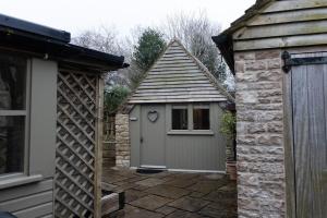 un pequeño cobertizo junto a un edificio de piedra en The Hideaway - A cosy retreat by the lakes, en South Cerney