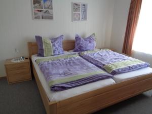 Una cama con sábanas y almohadas moradas. en Ferienwohnung Familie Renken, en Marienhafe