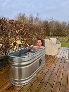 a man in a bath tub on a deck at Luxury Barn with sauna near York welcoming families, friends, groups in York