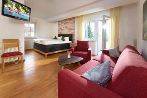 un salon avec un canapé rouge et un lit dans l'établissement Thermen Appartement Gabriela, 52 qm, à Bad Krozingen