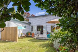 a house with a patio and an umbrella at Tūī Guesthouse in Cooks Beach