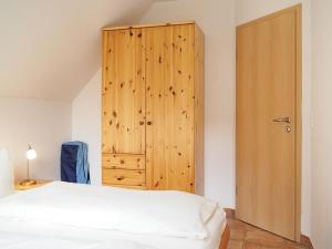 a bedroom with a bed and a wooden cabinet at FeWo 40 "Haus Kormoran - W3" in Prerow