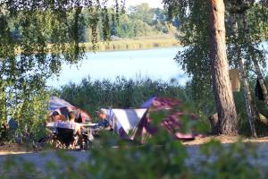 a group of people sitting at a table in front of a tent at Mobilheim 4 Personen MH10 in Hindenberg