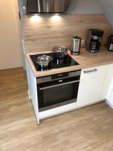 a kitchen with a stove with pots and pans on it at Ferienwohnung am Storchnest in Kenz +17 photos