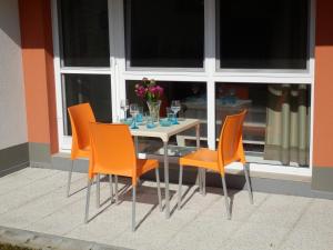 une table avec des chaises orange et une table avec des verres dans l'établissement Ubytování U lázní Aurora, à Třeboň