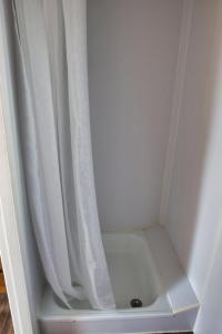 a shower with a white shower curtain next to a shower at Finnenhaus 1 in Lübeck