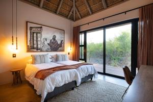 ein Schlafzimmer mit einem großen Bett und einem großen Fenster in der Unterkunft Villa Visvanger - Villa with river deck nearby Kruger in Hoedspruit + 47 Fotos