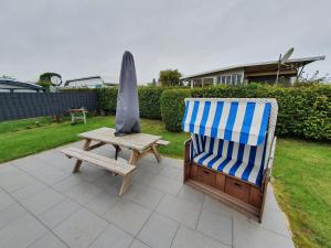 a chair and an umbrella next to a wooden table at Campingland Ostsee - Mobilheim 103Seewind in Schashagen