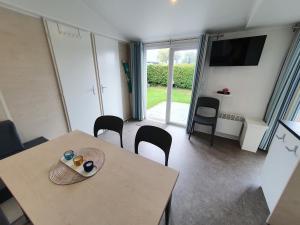 a room with a table and chairs and a television at Campingland Ostsee - Mobilheim 103Seewind in Schashagen