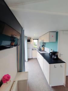a kitchen with white cabinets and a black counter top at Campingland Ostsee - Mobilheim 103Seewind in Schashagen +17 photos