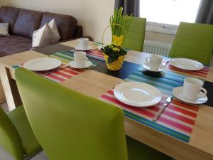 a dining room table with green chairs and a wooden table at Chalet Austernfischer am Kransburger See 547 in Kransburg