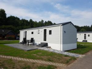 a small white building with a table and chairs at Chalet Alpenstrandläufer am Kransburger See 543 in Kransburg
