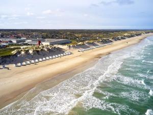 een luchtfoto van een strand met parasols en de oceaan bij 6 person holiday home on a holiday park in Blokhus in Blokhus