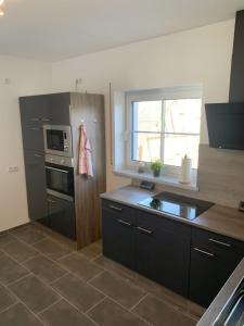 une cuisine avec des armoires noires et une fenêtre dans l'établissement Im Blauen Ländchen, à Lierschied