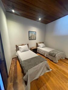 two beds in a room with wooden floors at Vesperata Diamantina in Diamantina