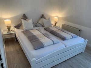 1 dormitorio con 1 cama blanca con almohadas y 2 lámparas en FeWo Woge, en Grödersby
