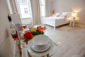 a glass table with a plate of food and a bottle of wine at Apartment No3 in Stralsund +4 photos