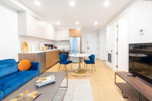 a living room with a blue couch and a kitchen at 202 New Condo 1BR in Prime Greenpoint in Brooklyn