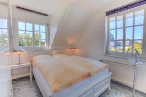 a white bedroom with a bed and two windows at Abaco 4N in Wenningstedt
