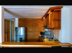 a kitchen with wooden cabinets and a brick wall at Suite Doble in Jericó +5 photos
