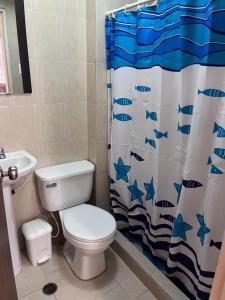 Un baño con inodoro y cortina de ducha con peces. en Ciudad Flamingo, Morrocoy chichiriviche, tucacas 7, en Chichiriviche
