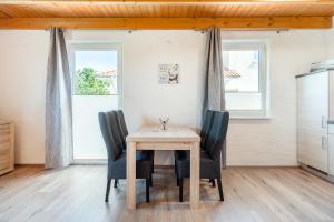 a table and chairs in a kitchen with two windows at Ferienwohnung Robbe für 2 Personen am Badesee Tannenhausen in Aurich