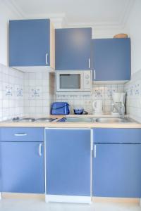 a kitchen with blue cabinets and a microwave at Windeby 5D in Wenningstedt