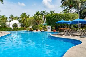 a swimming pool with chairs and umbrellas at Hotel Castillo Huatulco & Beach Club in Santa Cruz Huatulco