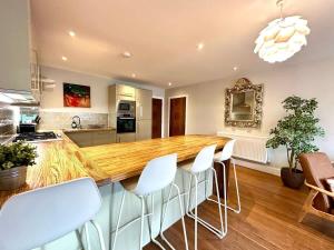 una cocina con un gran mostrador de madera con taburetes blancos en 2 Bed Garden Apartment, en Yarnton