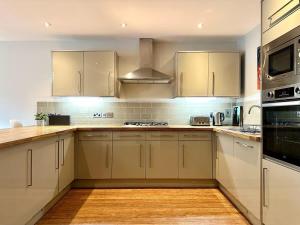 Una cocina con gabinetes blancos y un horno de estufa. en 2 Bed Garden Apartment, en Yarnton