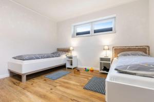 two beds in a bedroom with two windows at Ferienhof Marquardt Bungalow 3 in Fehmarn +2 photos