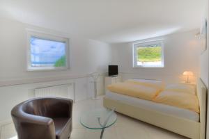 a white bedroom with a bed and a chair at Abaluga 1A in Wenningstedt